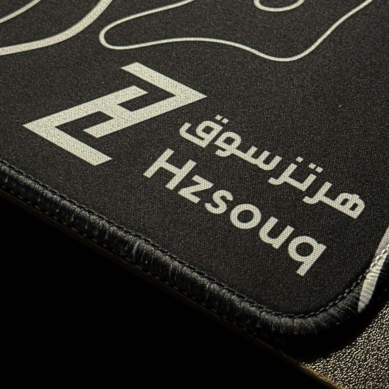 ماوس باد Black Flow أسود منظر قريب يعرض شعار هرتزسوق ونسيج القماش والأطراف المخيطة من هرتزسوق